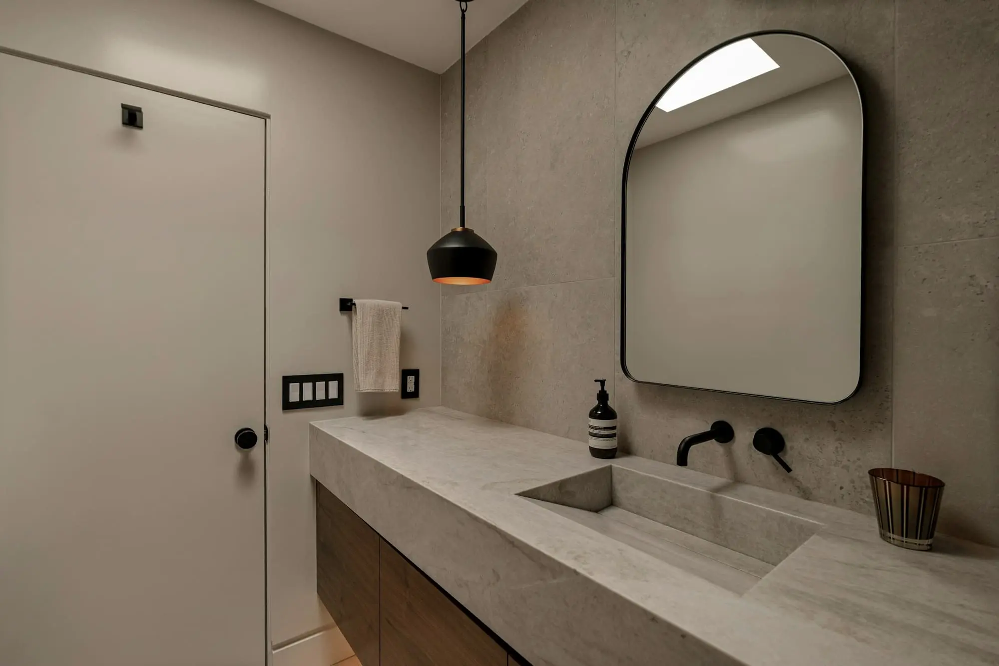 Stone trough basin with an arched mirror in a plaster-toned bathroom
