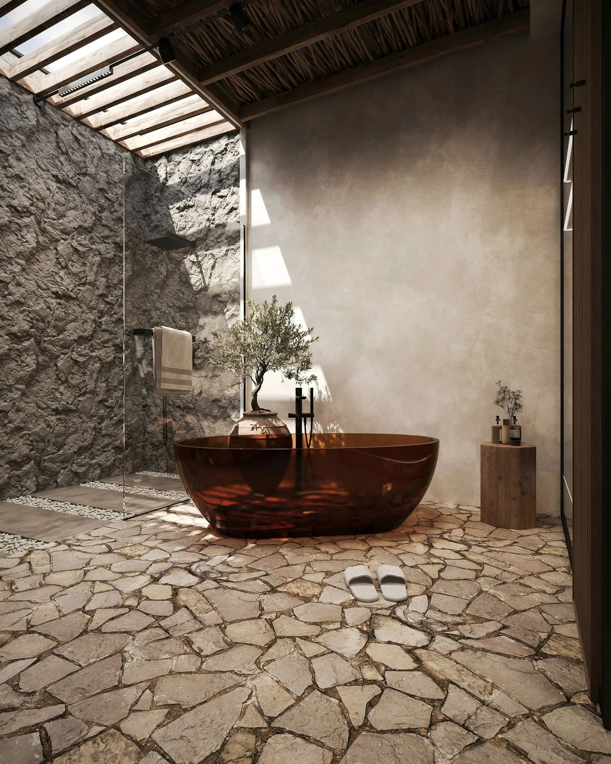 Freestanding amber bath in a stone-walled bathroom with a pebble floor
