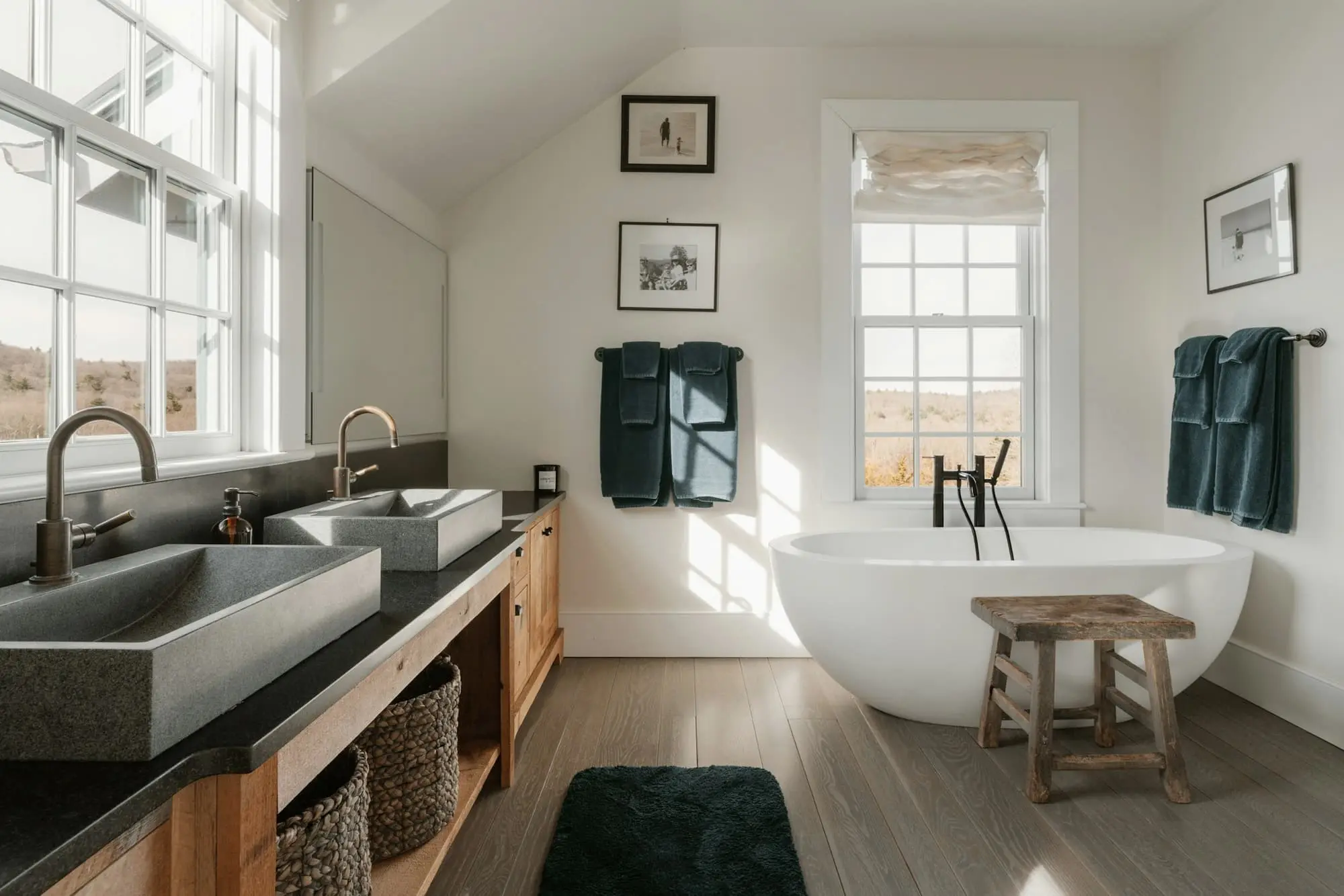 Bathroom with twin stone basins on an oak unit and a freestanding bath under a sash window