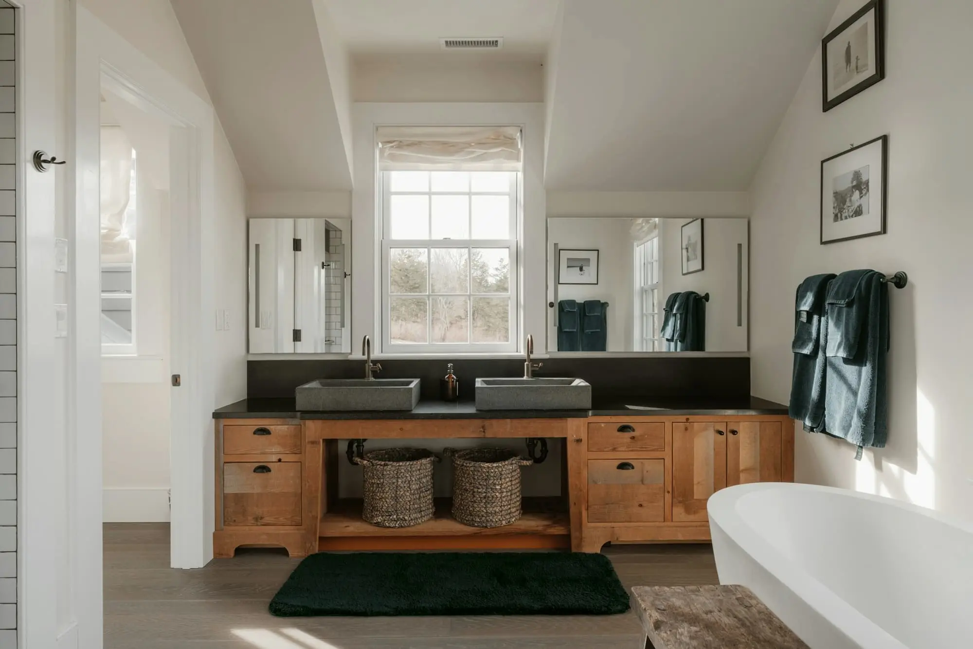 Under-eaves bathroom with an oak double vanity, a freestanding bath and a sash window