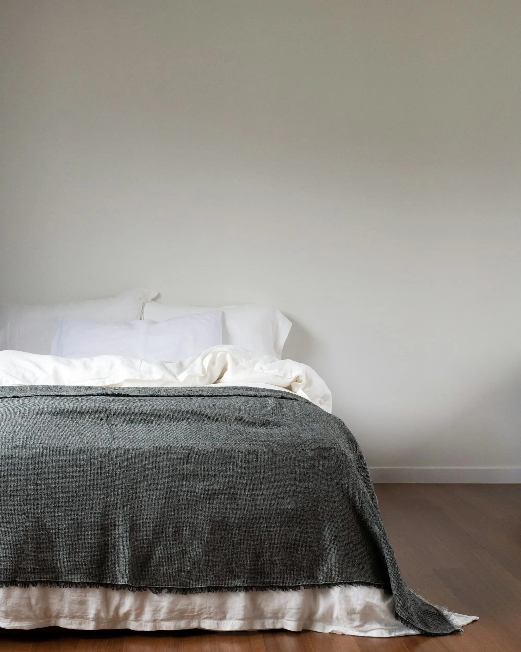 Calm bedroom with white linen and a grey wool throw