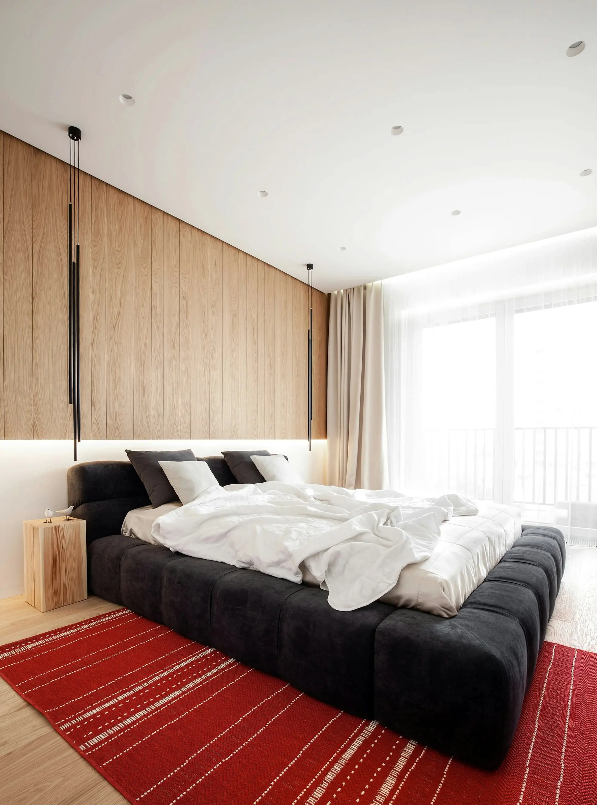 Bedroom with an oak-panelled wall, a dark upholstered bed and floor-length curtains