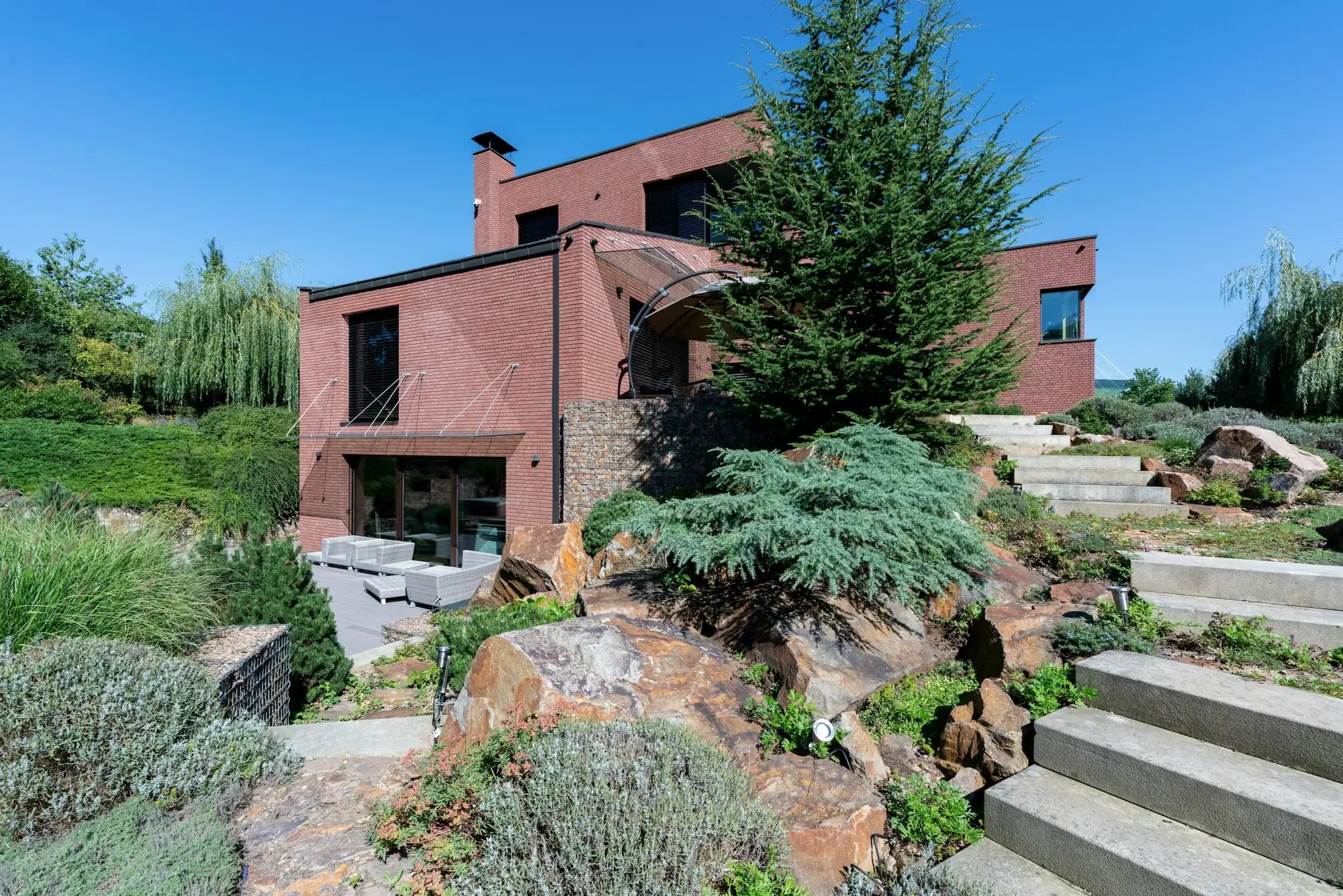 Red brick house with a stone staircase rising through a rock garden