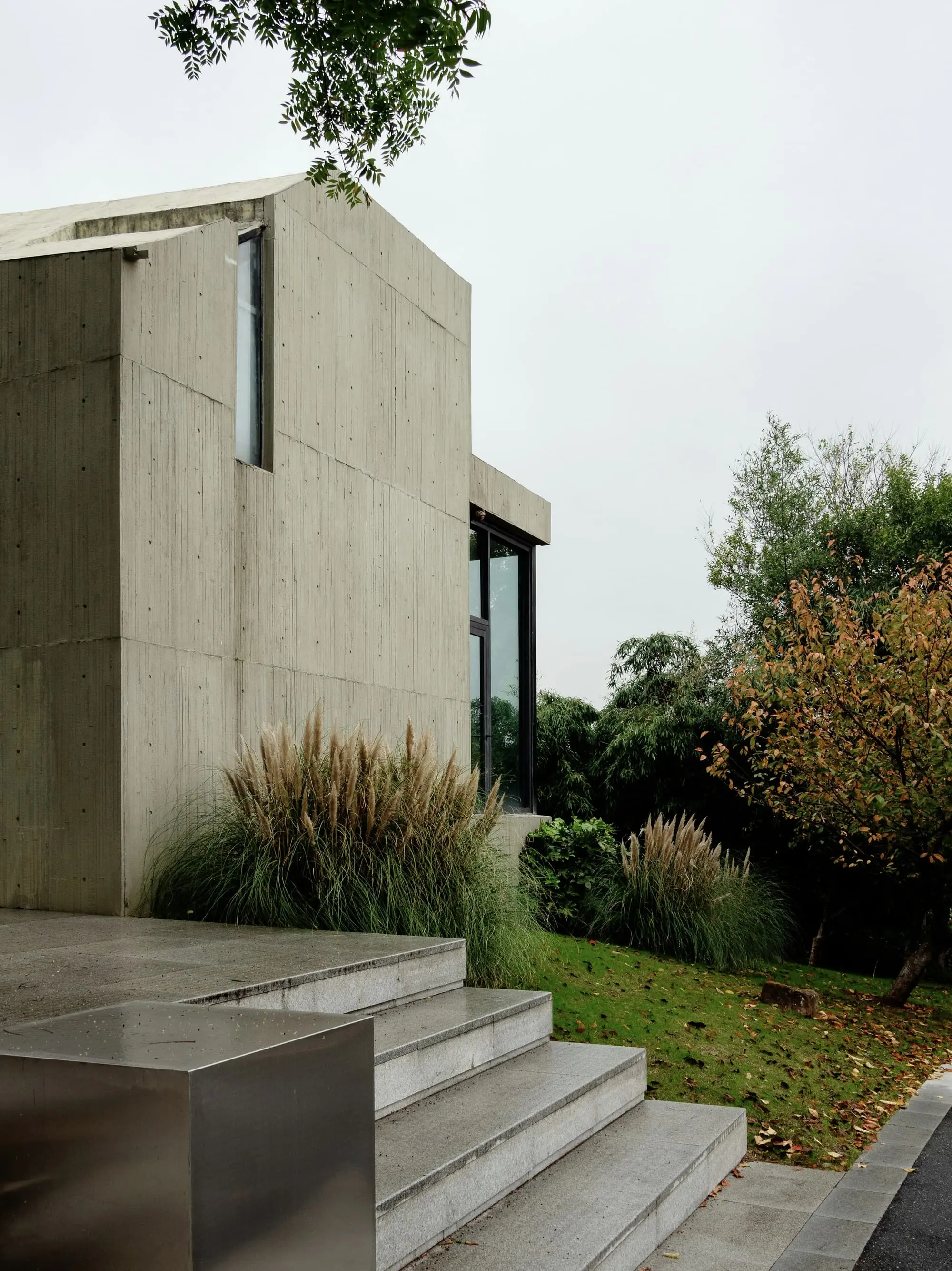 Board-marked concrete apartment building with ornamental grasses at its base