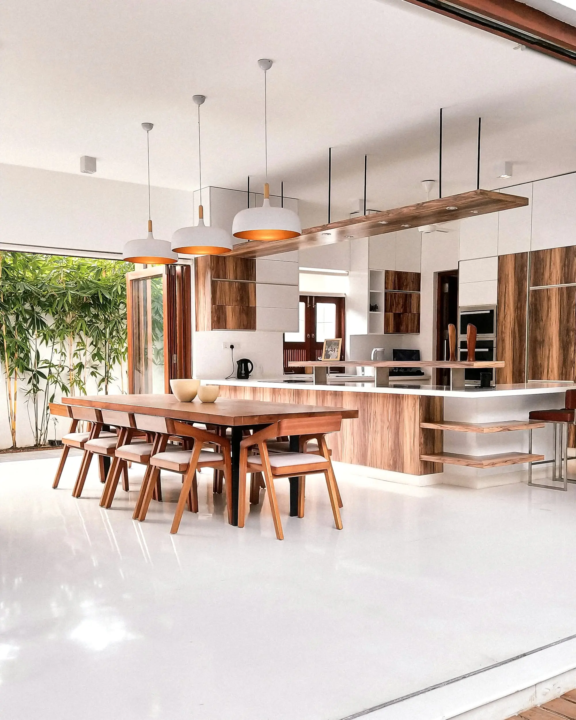 Open kitchen and dining space with a walnut island and slender pendant lights