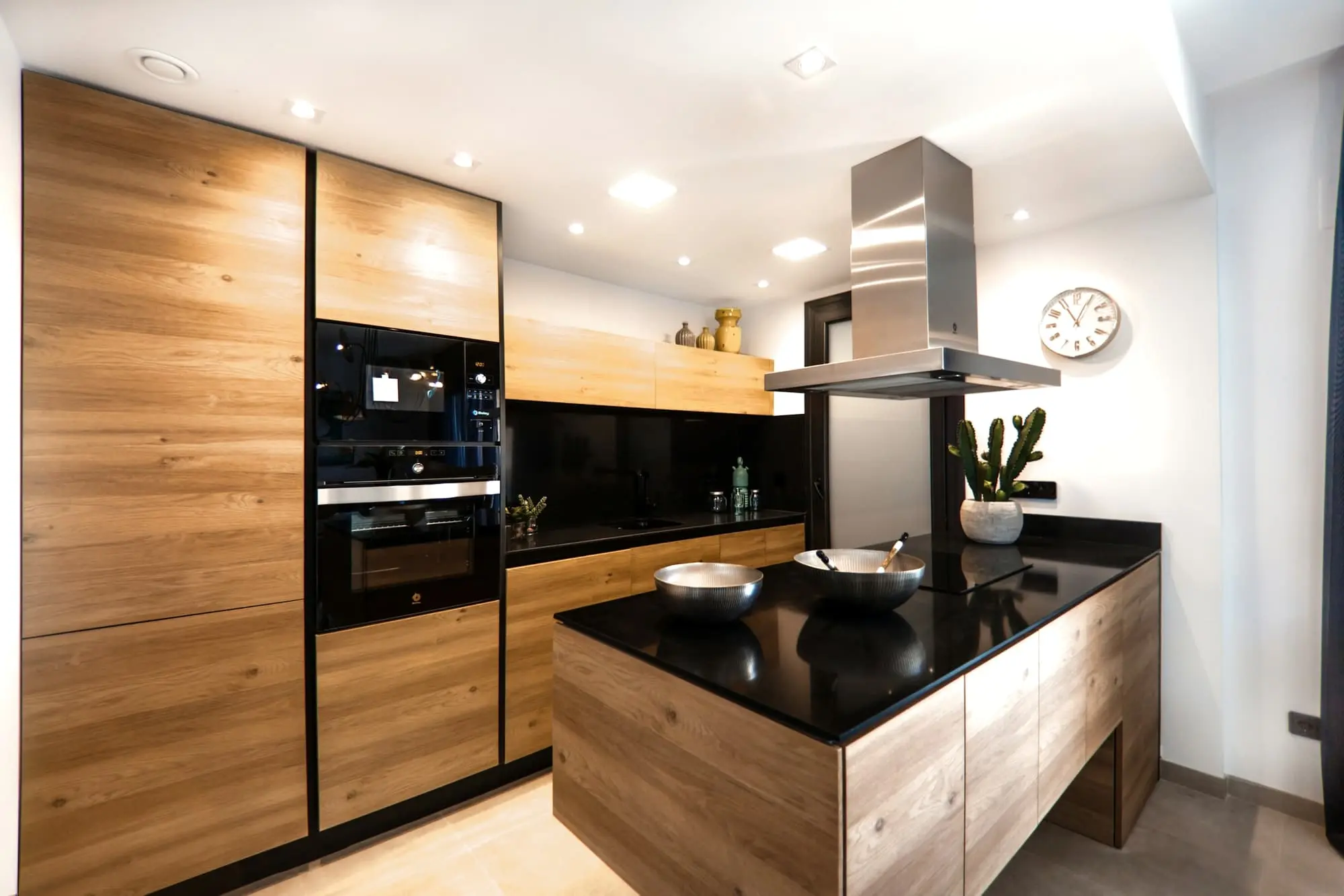 Oak kitchen with an island in black stone and a stainless extractor