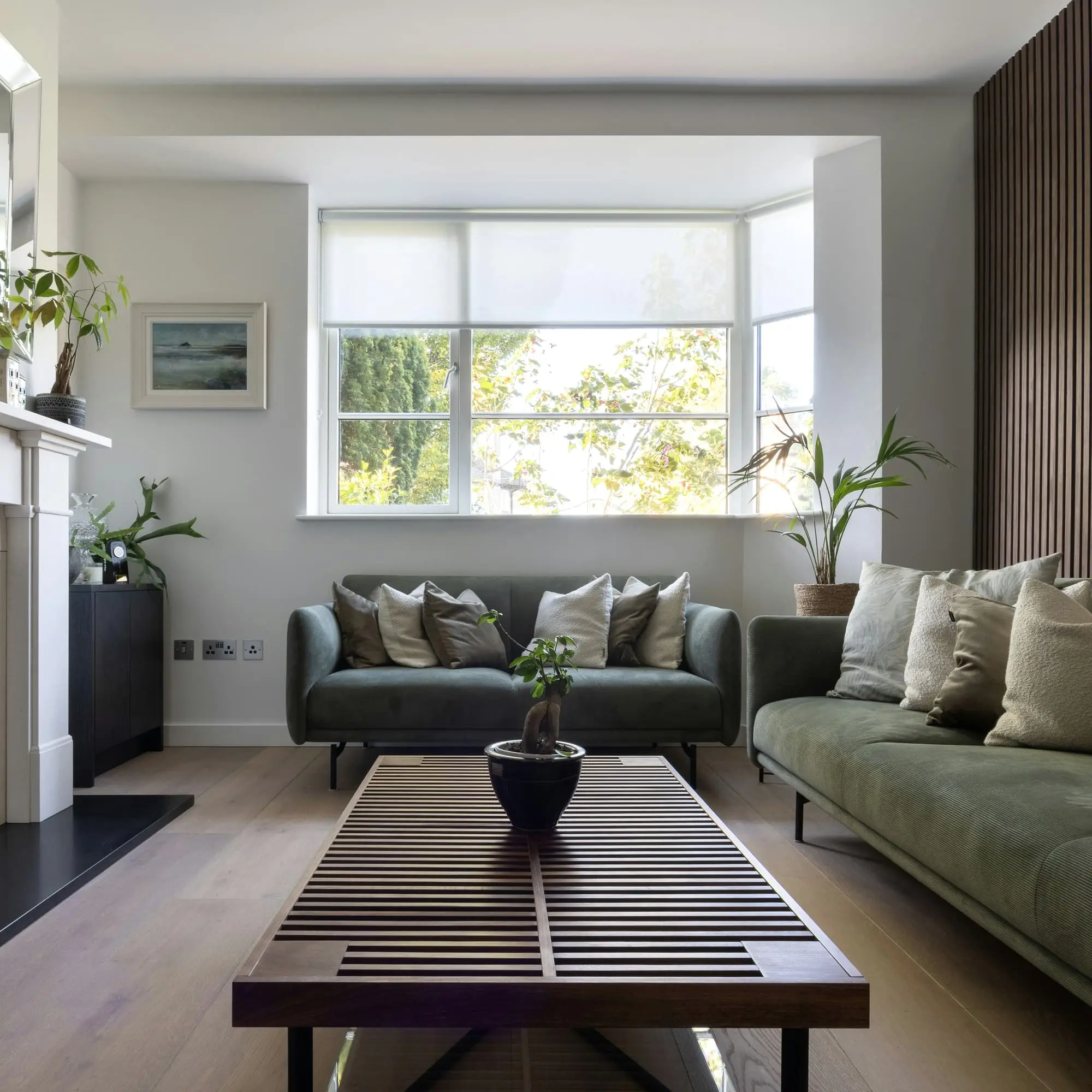Living room with a green sofa, oak flooring and a slatted coffee table