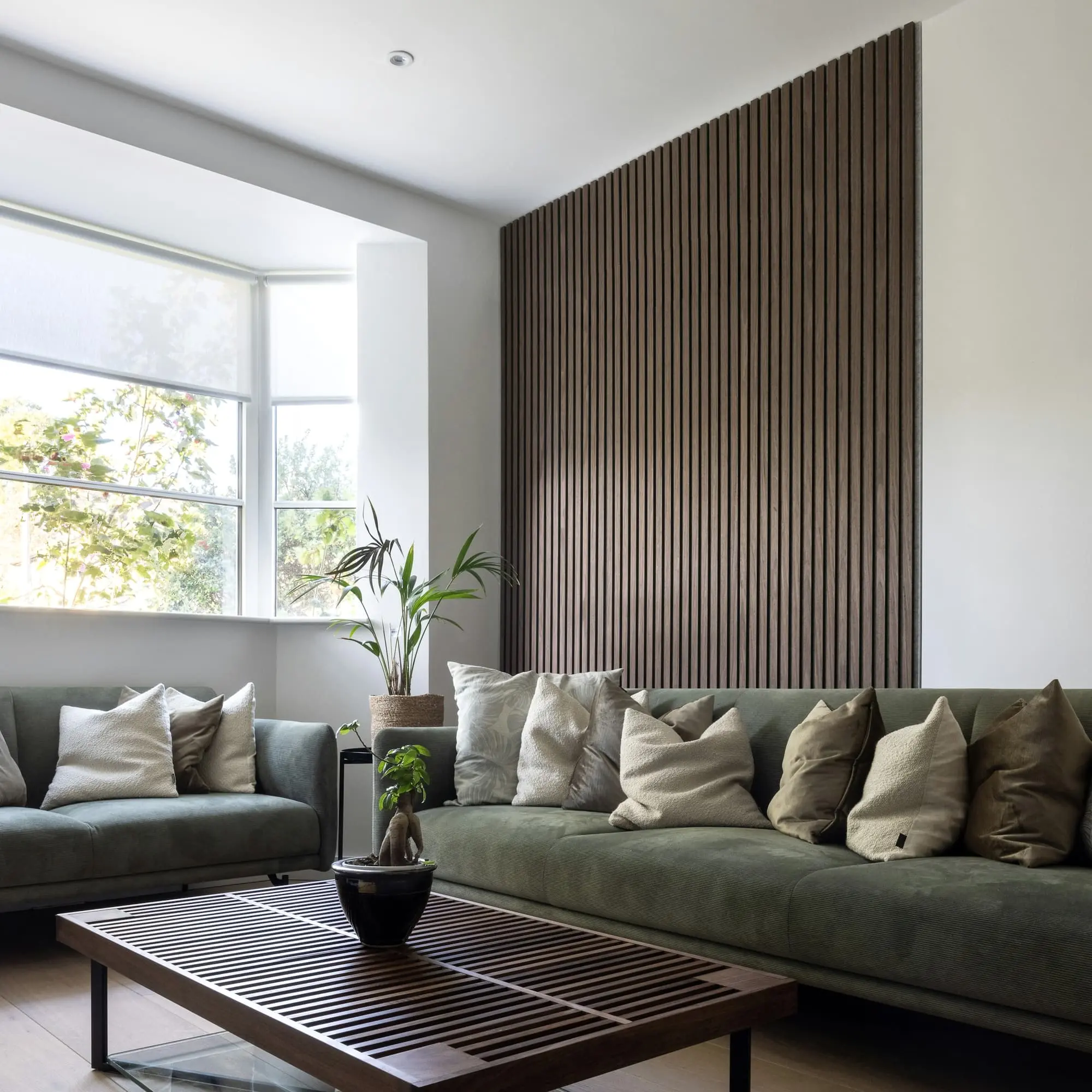 Living room with an oak slatted wall, a green sofa and a large bay window
