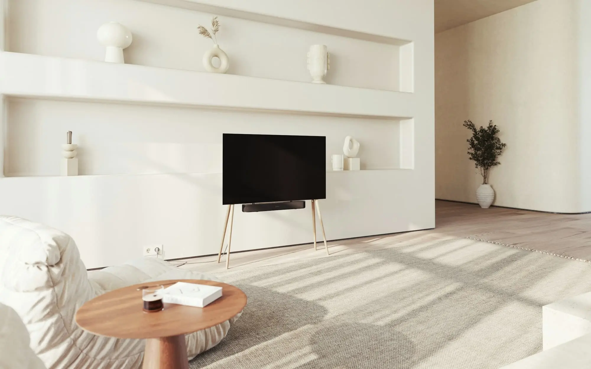 Light living room with a round oak coffee table and long shadows across the floor