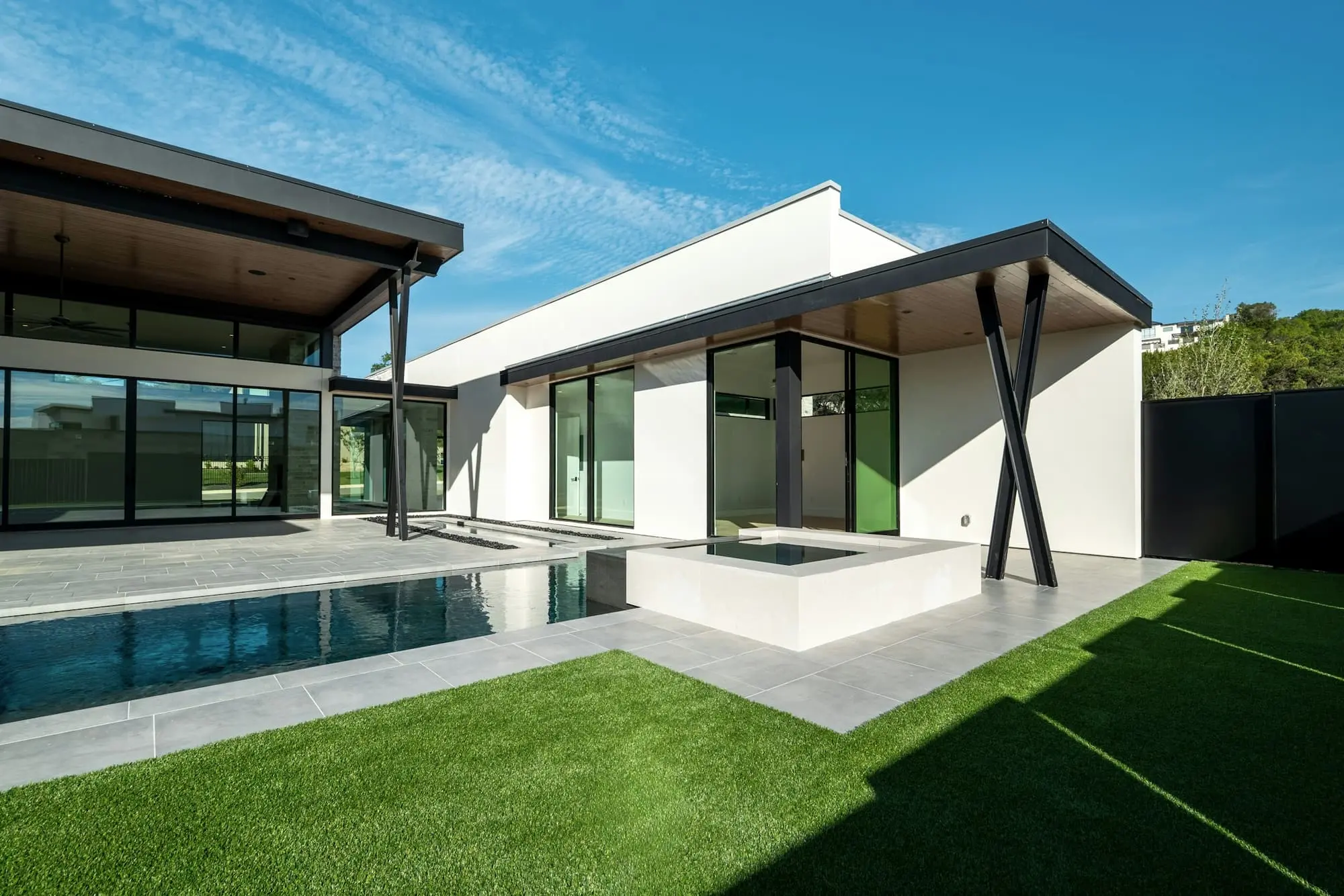 White house with a cantilevered roof, a swimming pool and a lawn